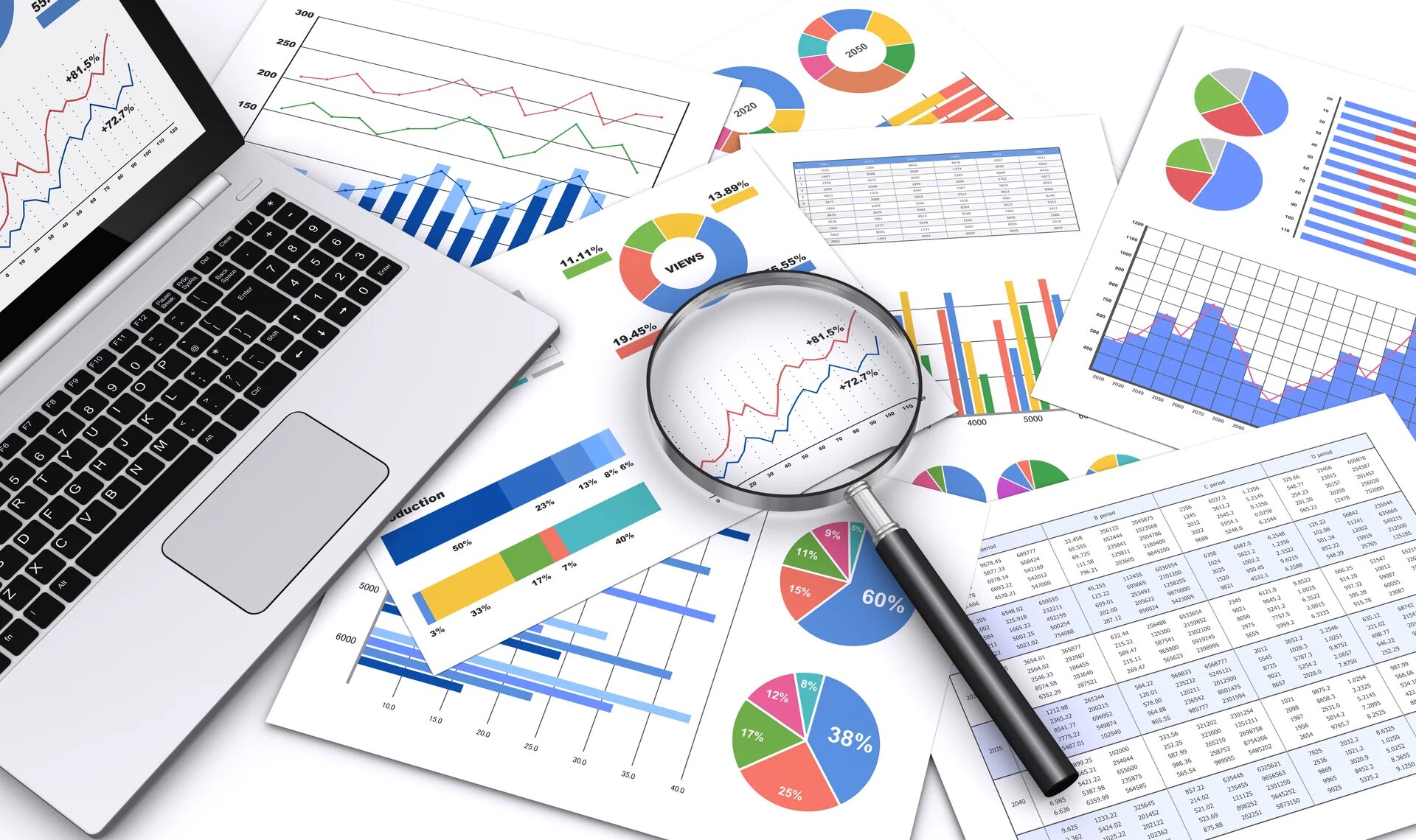 ordinateur et loupe posés sur une pile de graphiques