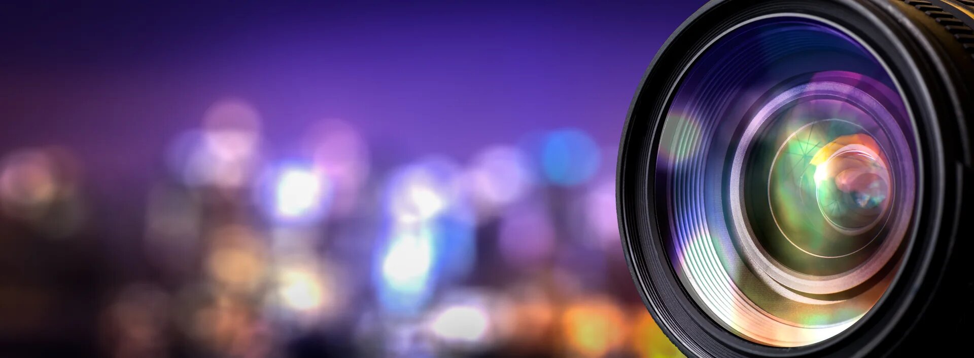 objectif d'appareil photo avec une ville la nuit éclairée et floue en arrière plan