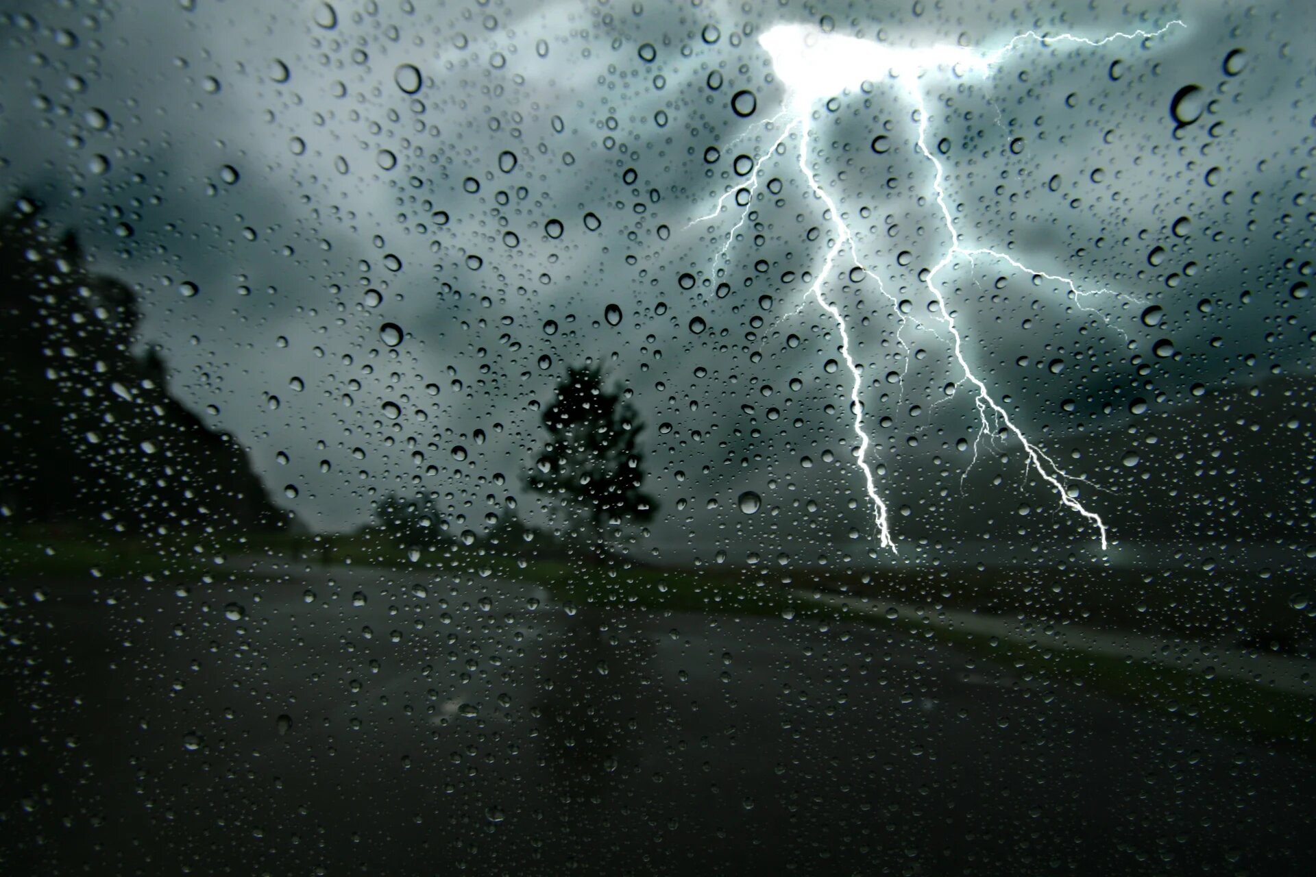 vitre recouverte de pluie qui donne sur éclair qui zèbre un ciel d'orage