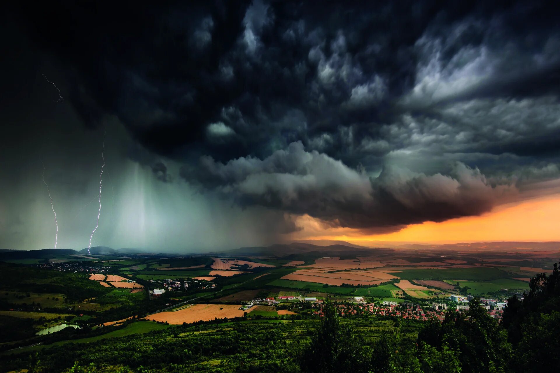 nuage noir menaçant au dessus d'un paysage de campagne et de cultures