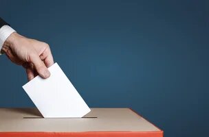 Main mettant un bulletin dans une urne électorale 