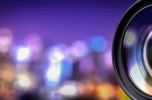 objectif d'appareil photo avec une ville la nuit éclairée et floue en arrière plan