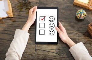 mains de femme qui tiennent une tablette avec des smileys de satisfaction