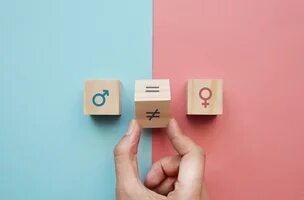 un cube avec le symbole masculin sur fond bleu face à un cube avec le symbole féminin sur fond rose. Entre les deux, un cube qu'une main fait passer de la face "inégal" à "égal"